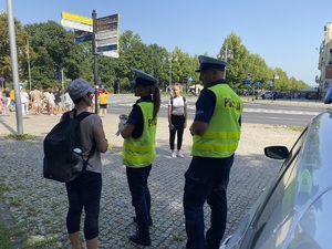 policjant i policjantka rozmawiają z kobietą przed przejściem dla pieszych