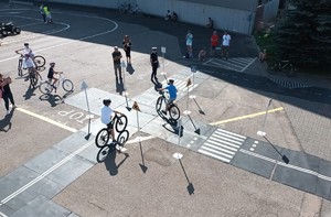 zdjęcie widziane&amp;quot; z lotu ptaka&amp;quot; przedstawia policjantkę stojącą na miasteczku rowerowym oraz grupę dzieci podczas zdawania egzaminu