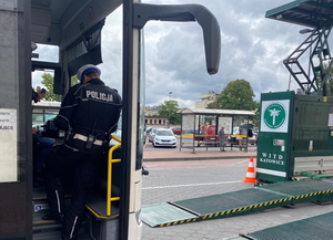 policjant stoi w drzwiach autobusu, w tle mobilna stacja diagnostyczna