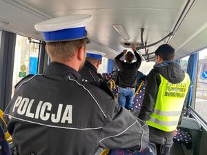 w środku autobusu policjanci, funkcjonariusze inspekcji transportu drogowego i kierowca sprawdzają okno dachowe w pojeździe