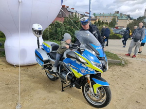 chłopiec pozuje do zdjęcia na policyjnym motocyklu, obok stoi policjant