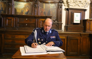 podkomisarz Rafał Jankowski dokonuje wpisu do księgi pamiątkowej Komendy Miejskiej Policji w Częstochowie
