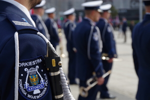 zbliżenie na naszywkę na ramieniu munduru policjanta z orkiestry policji w Katowicach, w tle policjanci z instrumentami