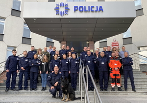 na schodach przed wejściem głównym do komendy stoi grupa policjantów i pracowników, biorących udział w organizacji szkolenia