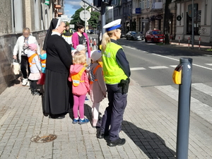 policjantka z ruchu drogowego przeprowadza grupę dzieci przez przejście dla pieszych