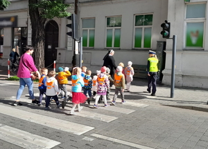 policjantka z ruchu drogowego przeprowadza grupę dzieci przez przejście dla pieszych