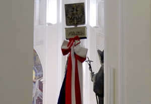 czubek sztandaru z napisem Policja podczas mszy, w tle figura Jana Pawła II