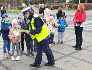 policjantka rozdaje przechodniom odblaski