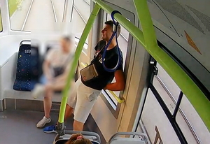 młody mężczyzna ubrany w czarna koszulkę z krótkim rękawem siedzi tyłem do kierunku jazdy w tramwaju