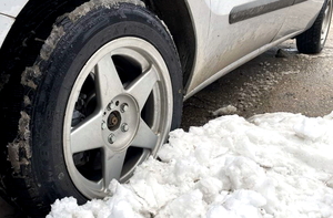 na zdjęciu zbliżenie na tylne koło samochodu, obok usypana kupka śniegu