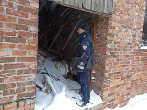Policjant przed wejściem do opuszczonego budynku