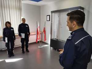 Komendant w mundurze stoi na wprost dwóch policjantów