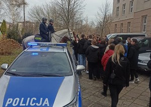 Policyjny patrol konny stoi wśród młodzieży-obok zaparkowany radiowóz
