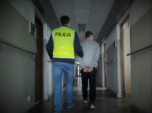 Policjant doprowadza zatrzymanego