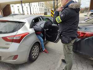 Zatrzymany wysiada z pojazdu- obok stoi policjant