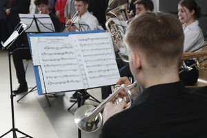 Chłopak gra na instrumencie- w tle zeszyt z nutami