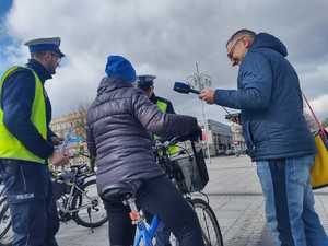 Policjanci i dziennikarz rozmawiają z rowerzystką