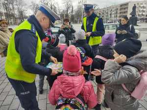 Policjanci rozmawiają z dziećmi i wręczają im opaski odblaskowe