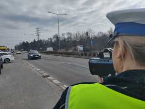 Policjantka miernikiem prędkości mierzy w kierunku nadjeżdżających pojazdów