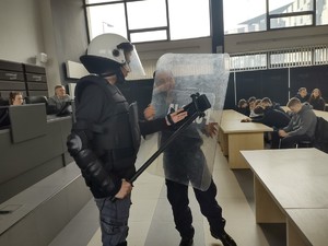 Policjant prezentuje na jednym z uczniów strój bojowy policjanta