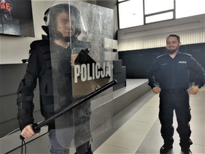 Uczeń prezentuje się w policyjnym stroju bojowym- obok stoi umundurowany policjant