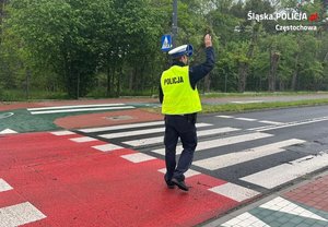 Policjant wchodzi na przejście dla pieszych i unosi prawa rękę