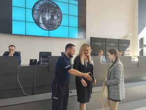 Policjant wyciąga dłoń w stronę laureatki, która zbliża się na środek sali