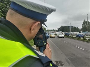Policjant z miernikiem prędkości stoi na drodze