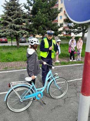 Policjant rozmawia z dzieckiem, które stoi z rowerem