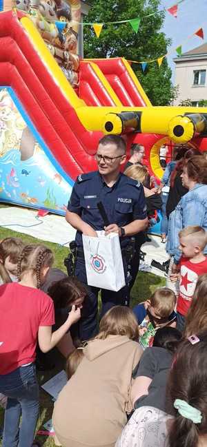 Policjant na placu zabaw rozdaje dzieciom opaski odblaskowe