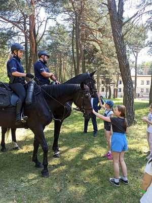 Policyjni jeźdźcy na koniach witają się z dziećmi