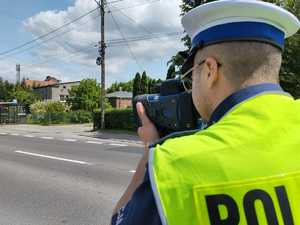 Policjant z miernikiem prędkości stoi przy drodze