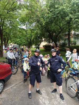 Policjanci pozują do zdjęcia- w tle dzieci na rowerach gotowe ruszyć w trasę