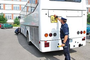 Policjant sprawdza autokar, czy jego stan techniczny jest poprawny