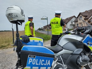 Zaparkowane motocykle służbowe a przy nich policyjny patrol stoi przy drodze