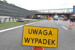 Na zdjęciu widoczny znak z napisem &quot;uwaga wypadek&quot;, w tle droga.