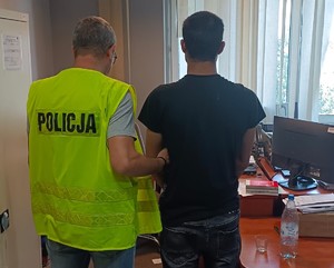 Policjant doprowadza zatrzymanego do pomieszczenia służbowego