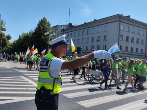 Policjant kieruje pieszych, przechodzących przez jezdnię po pasach