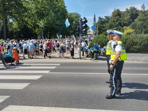 Policyjny patrol czuwa przy przejściu dla pieszych po którym idą pielgrzymi