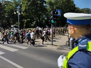 Policjant czuwa nad bezpieczeństwem pieszych, którzy idą przez jezdnie po pasach