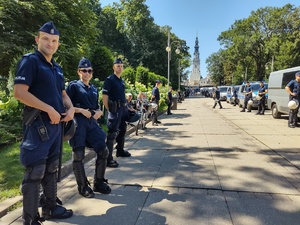 Policjanci stoją w szeregu wzdłuż alei