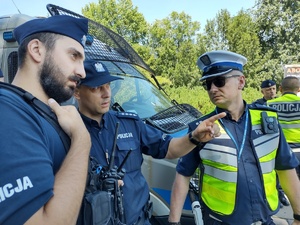 Policjanci omawiają sytuację, jeden z nich wskazuje palcem