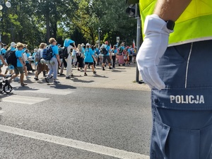 Policjant w rękawiczce czuwa nad przemarszem pieszych przez jednię