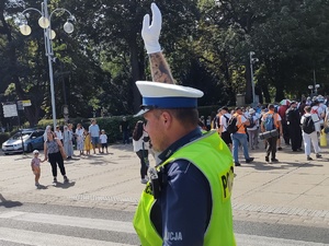 Policjant na drodze unosi prawą rękę do góry