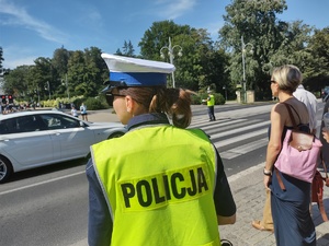 Policjantka stoi przy drodze i pilnuje bezpieczeństwa