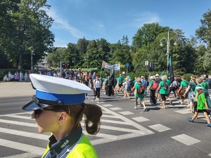 Policjantka stoi przy przejściu dla pieszych i dba o bezpieczny przemarsz pielgrzymów