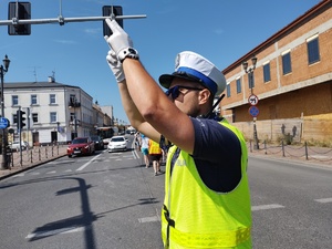 Policjant kieruje ruchem na drodze, unosi dwie ręce