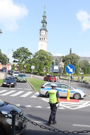 Policjant na drodze kieruje ruchem, w tle widoczna wieża jasnogórska