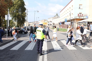 Policjant stoi przy przejściu dla pieszych i czuwa nad bezpieczeństwem pieszych