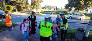 Policjanci wręczają elementy odblaskowe dzieciom, które prawidłowo przeszły przez przejście dla pieszych